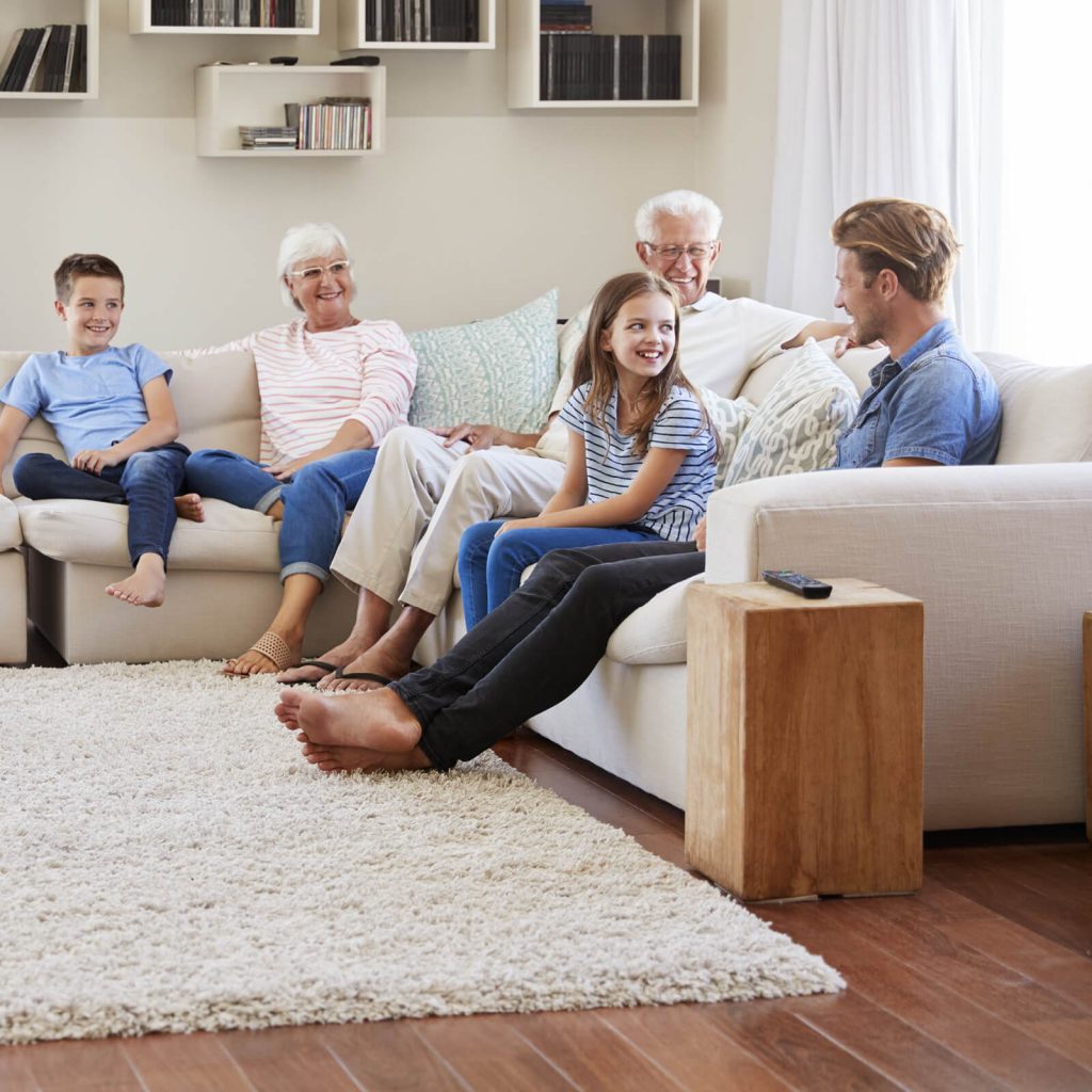 Happy family sitting on living room sofa | H&R Carpets and Flooring